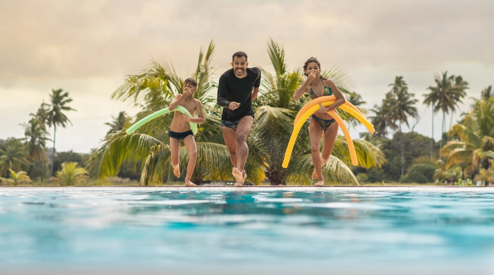Family running towards pool with floaties.
