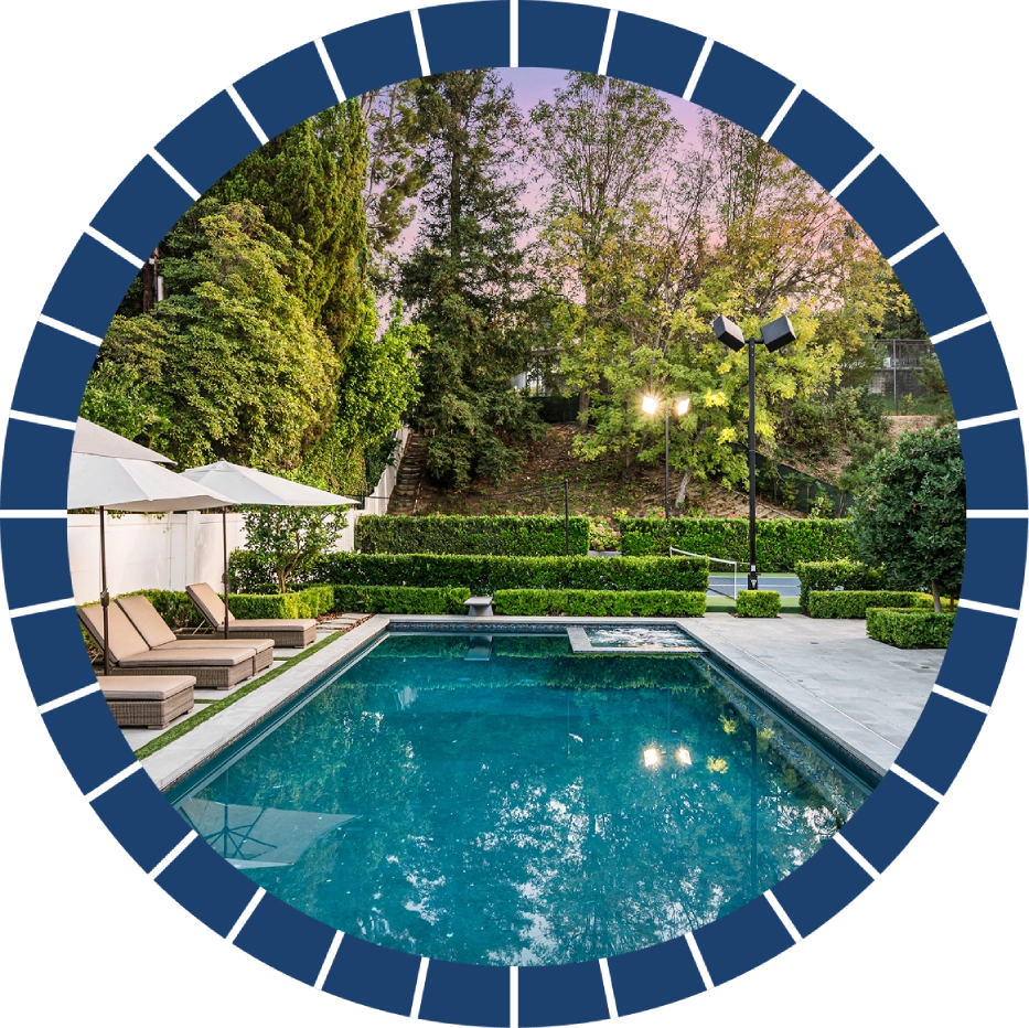 Luxurious poolside with trees and loungers.